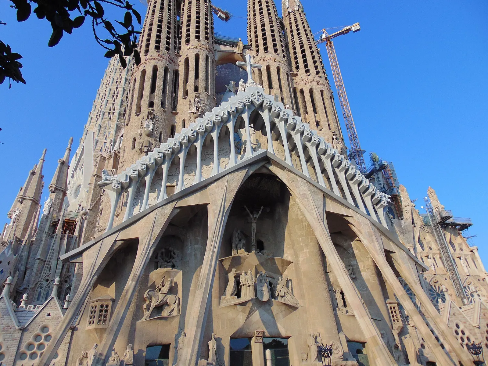 The Passion facade and towers of the Sagrada Família against a blue sky